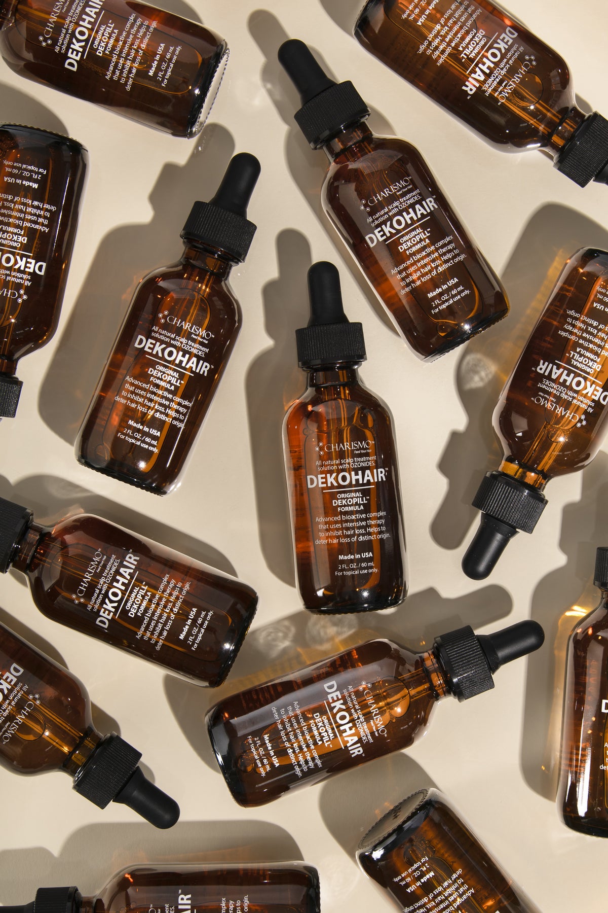 DEKOHAIR Serum bottles laid out on a warm ivory ground